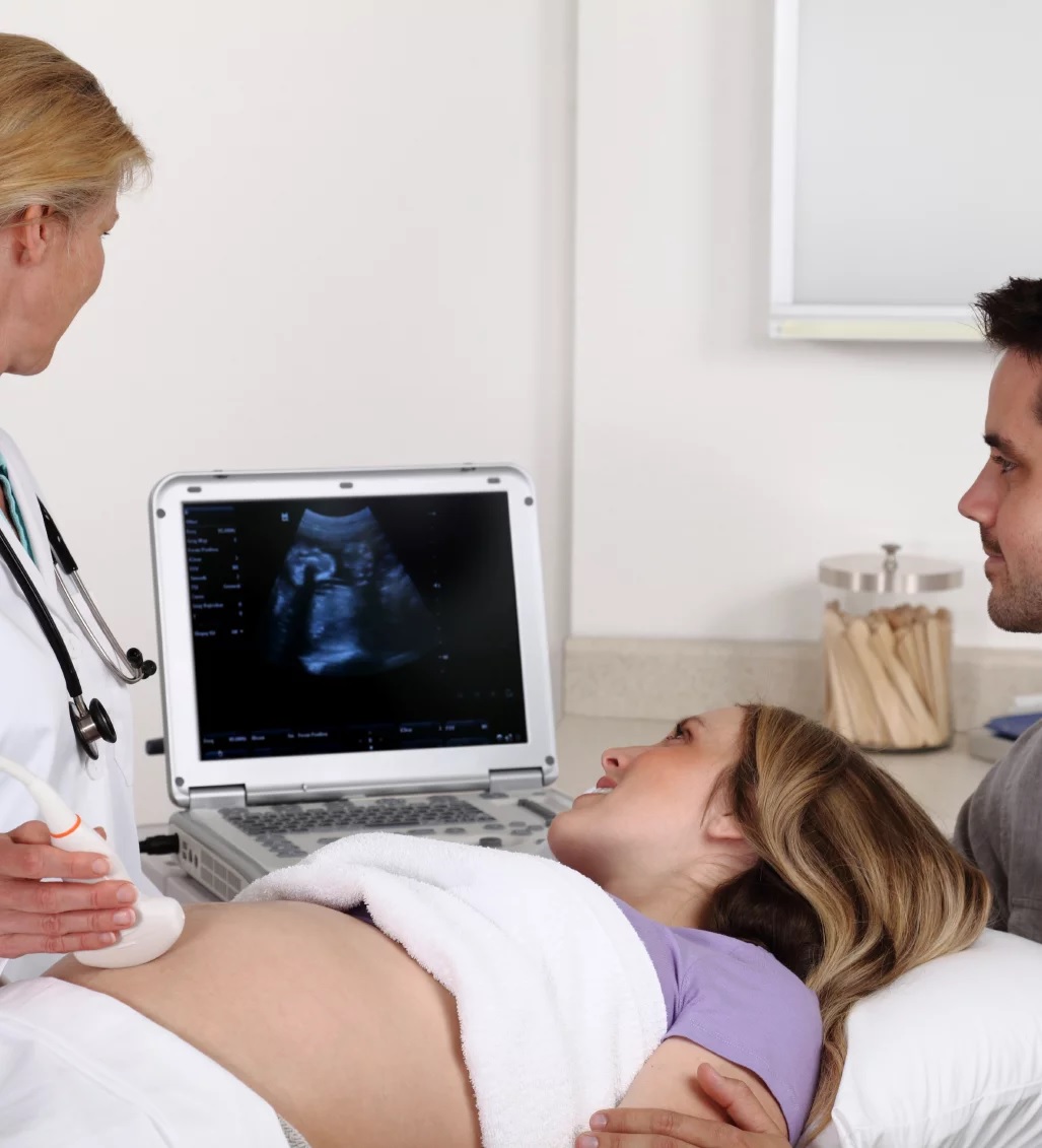 Doctor performing an ultrasound scan for a pregnant woman with her partner.